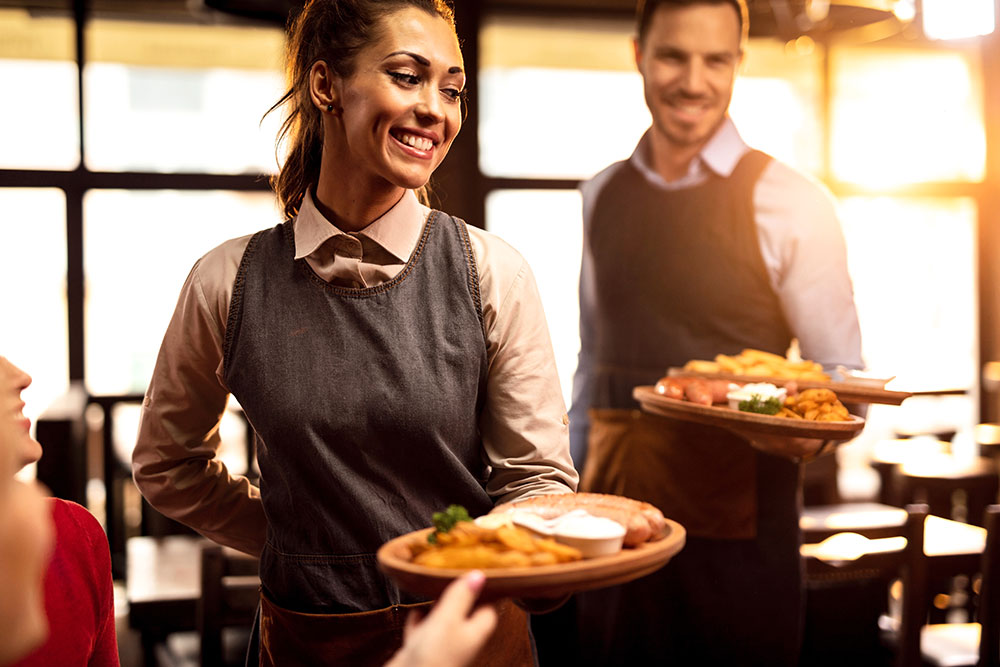 Männliche und weibliche Servicekräfte servieren Teller im Restaurant
